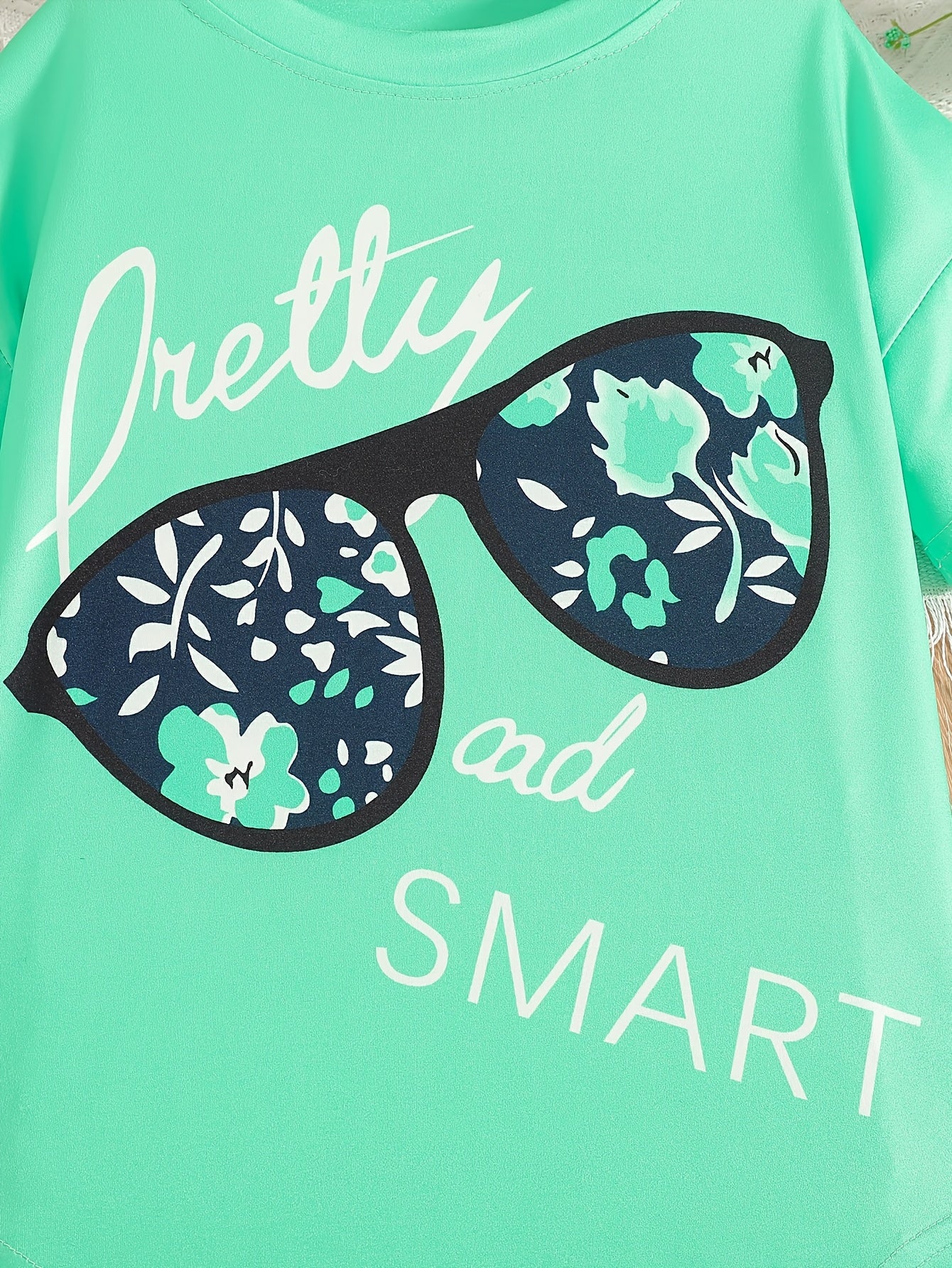 Ensemble de 2 pièces pour filles avec impression de grandes lunettes et motif de citation, t-shirt loose à épaules dénudées avec design asymétrique + leggins courts à imprimé floral du 4 au 8 ans